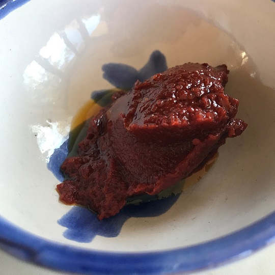 Photo of a dollop of rich red tomato paste in a small white and blue bowl